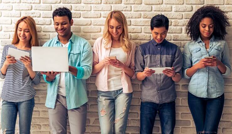 five people looking at various devices